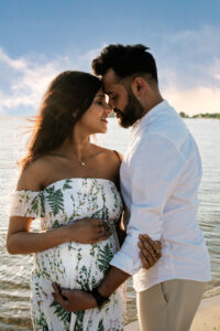 Zwangerschapsshoot op het strand met romantische dubbele belichting van verliefd stel in boho stijl