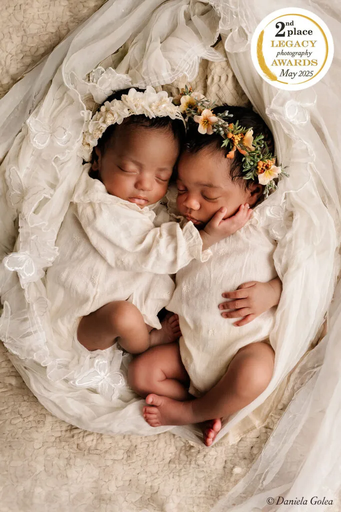 Twee pasgeboren tweelingbaby’s slapend samen, gekleed in witte outfits met bloemenhoofdbanden, gefotografeerd in Almere.
