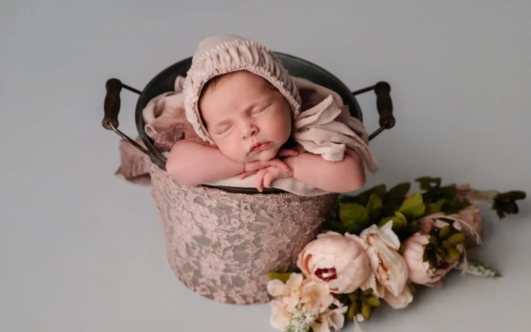 Pasgeboren baby in een witte doek hanger, veilig gefotografeerd door gecertificeerde newborn fotograaf in Almere