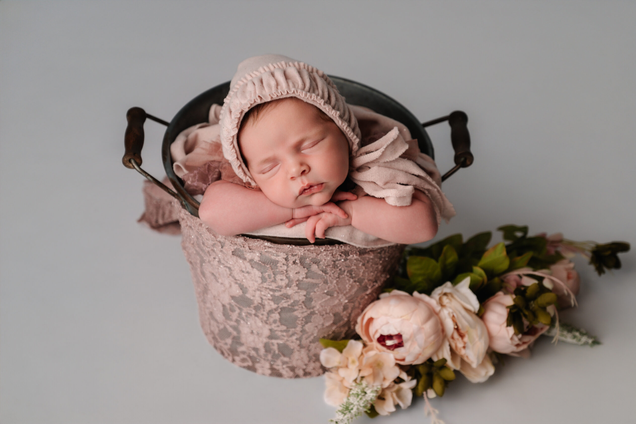 Pasgeboren baby in een witte doek hanger, veilig gefotografeerd door gecertificeerde newborn fotograaf in Almere