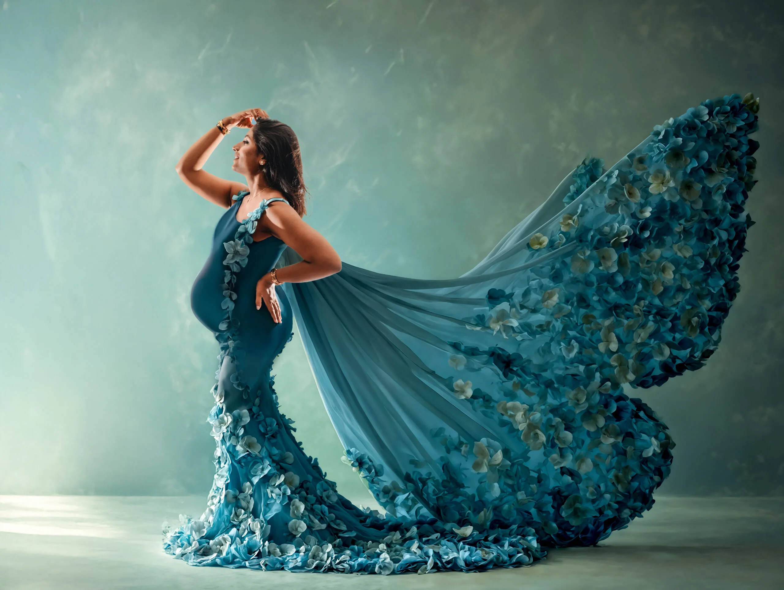 Artistieke Zwangerschapsshoot in Vlinderjurk – Almere Zwangere vrouw poseert in een elegante blauwe jurk met bloemen en lange sleep in vlindervorm, tijdens een artistieke zwangerschapsshoot