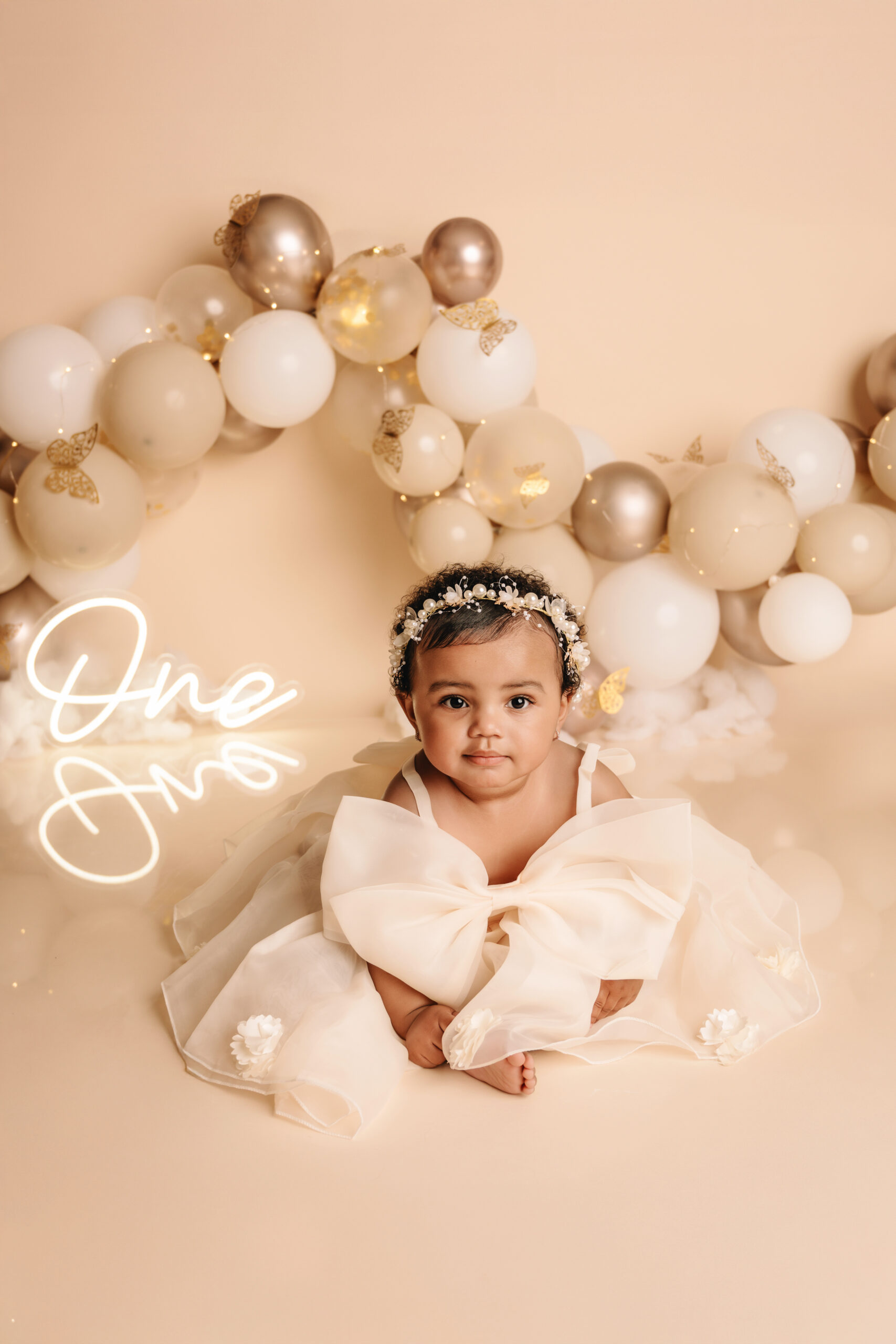 Baby meisje tijdens 1 jaar fotoshoot in Almere met beige jurk en ballonnen decor in studio