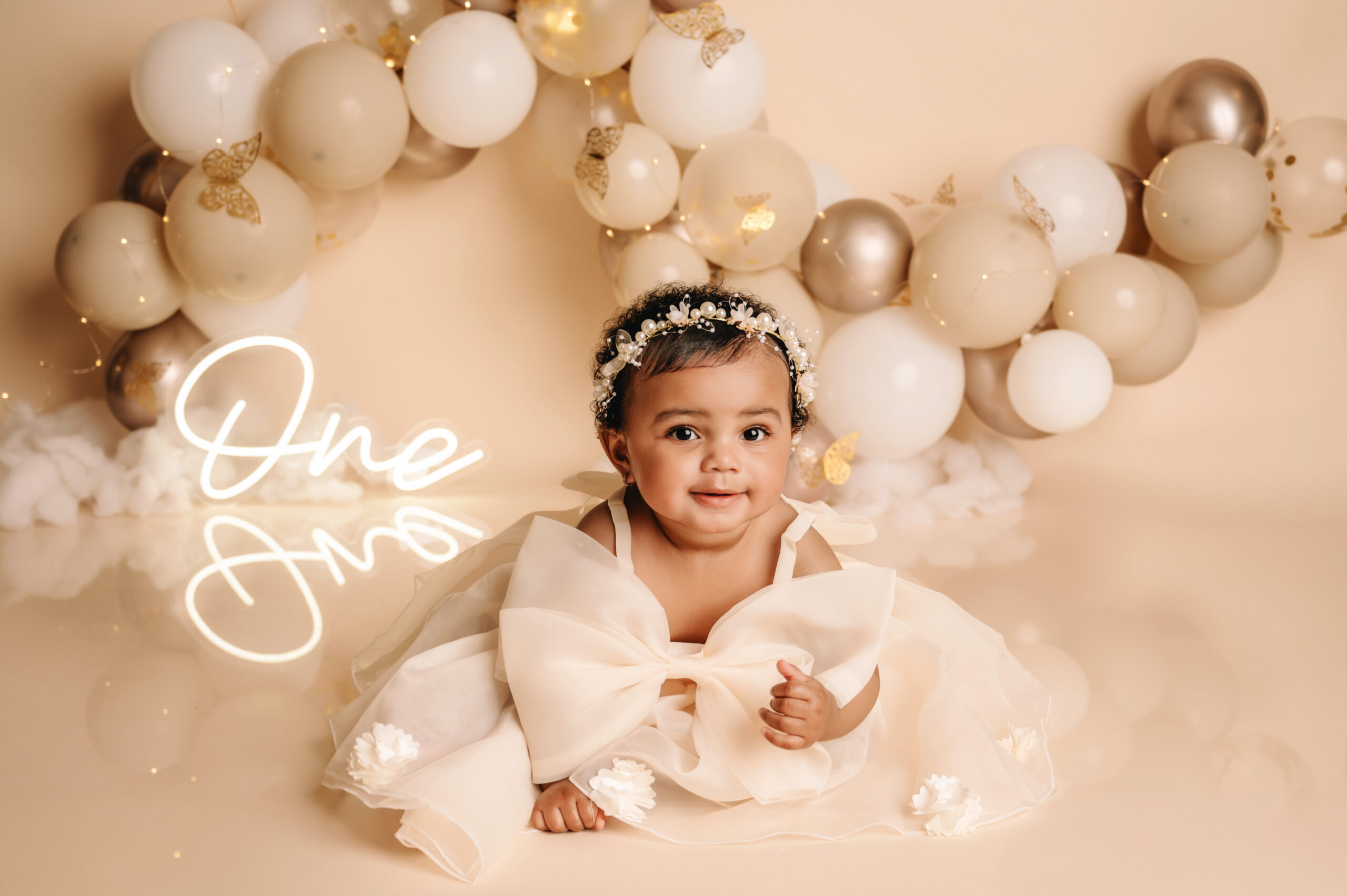 Baby meisje tijdens 1 jaar fotoshoot in Almere met beige jurk en ballonnen decor in studio