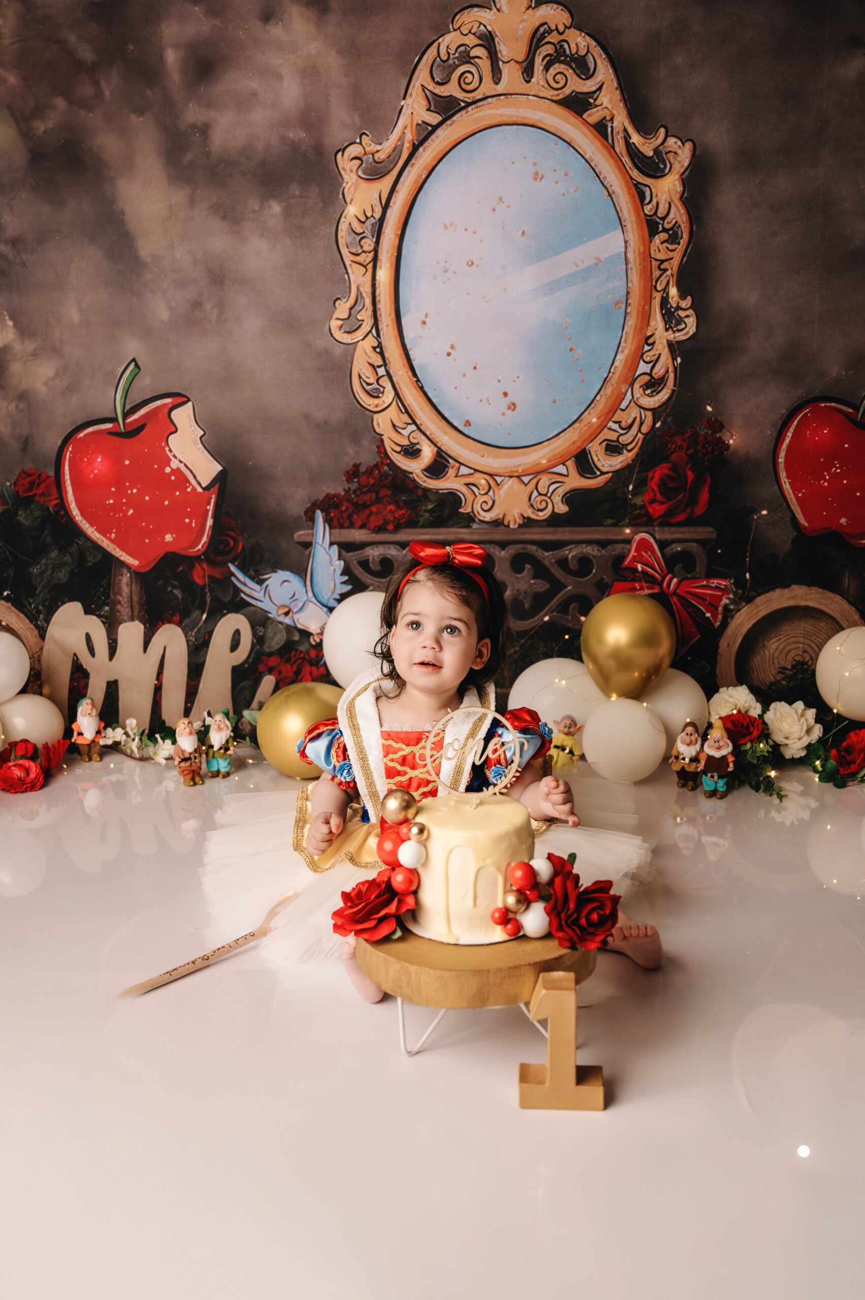 Cake smash fotoshoot in Almere van een meisje in Sneeuwwitje jurk met verjaardagstaart in sprookjes decor