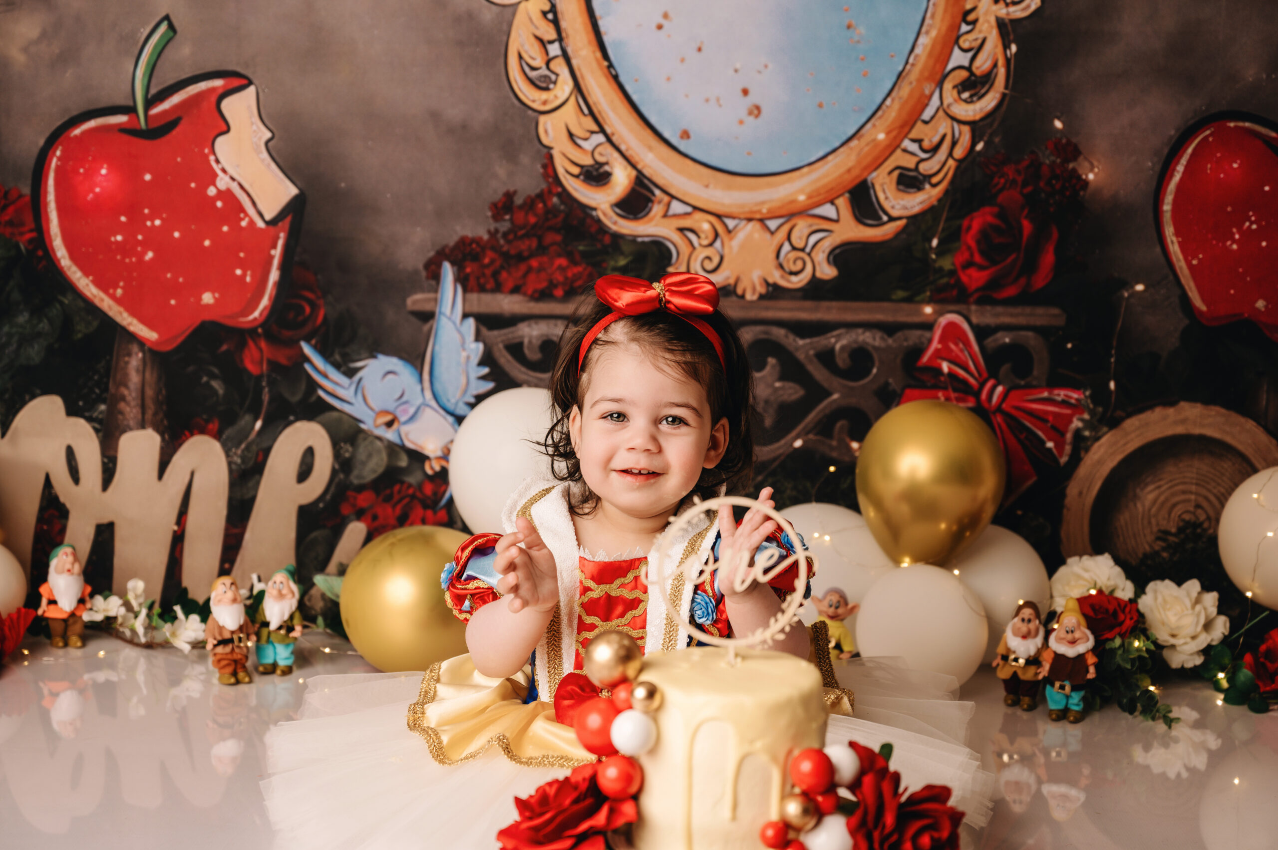 Cake smash fotoshoot in Almere van een meisje in Sneeuwwitje jurk met verjaardagstaart in sprookjes decor