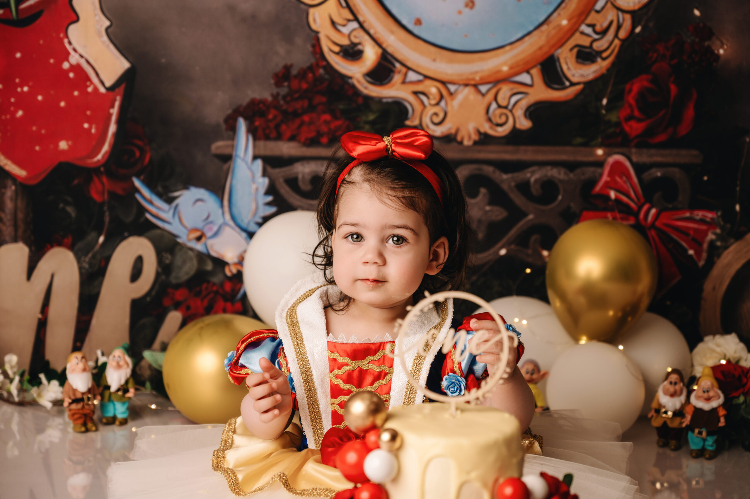 Cake smash fotoshoot in Almere van een meisje in Sneeuwwitje jurk met verjaardagstaart in sprookjes decor