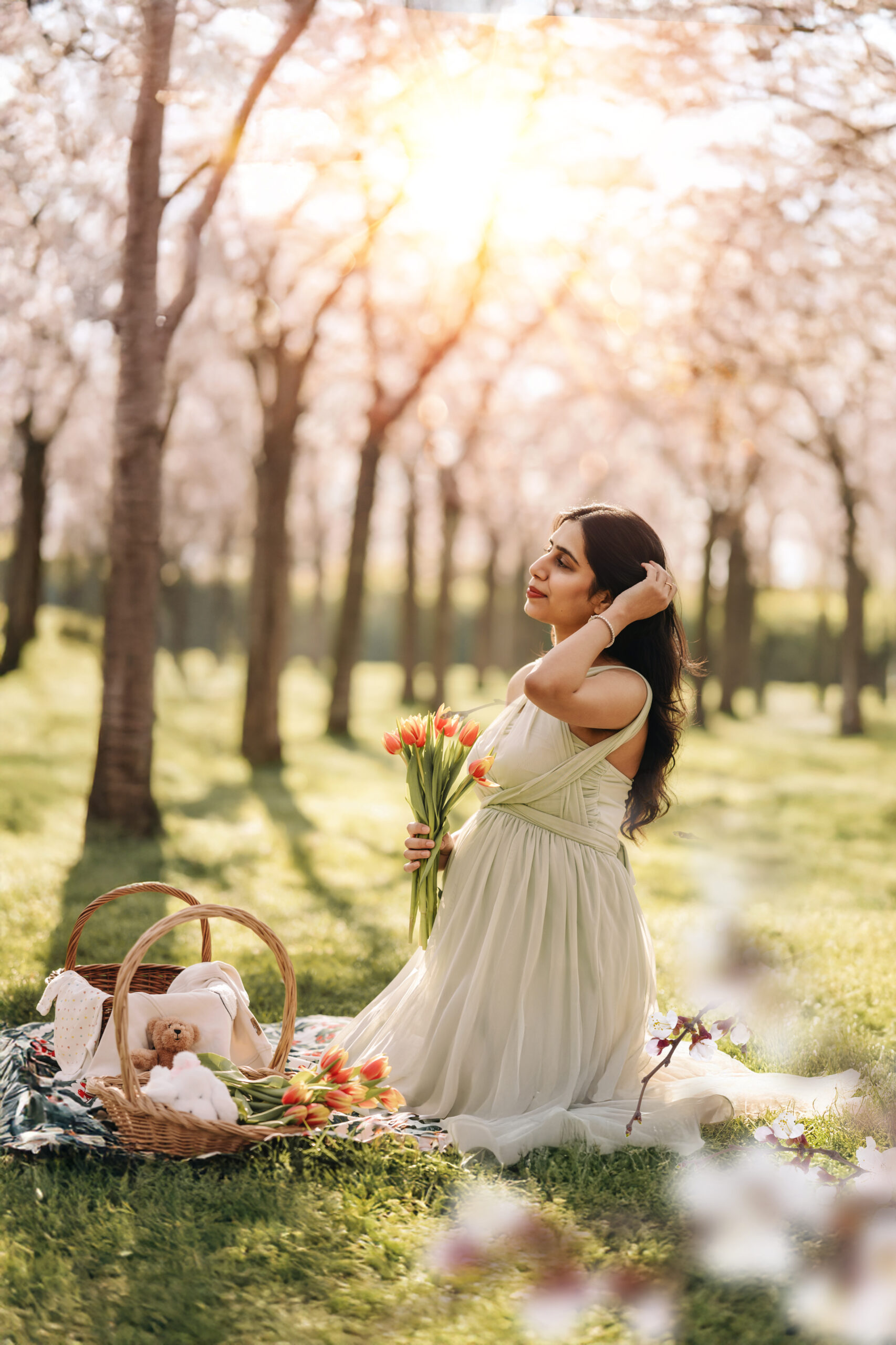Pregnant woman standing under pink cherry blossom trees during a dreamy spring maternity photoshoot in Amstelveen